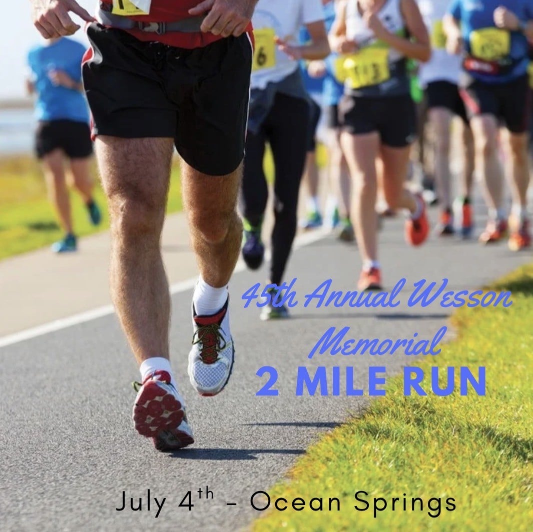 Runners participate in a road race event, with text promoting the 45th Annual Wesson Memorial 2 Mile Run on July 4th in Ocean Springs.